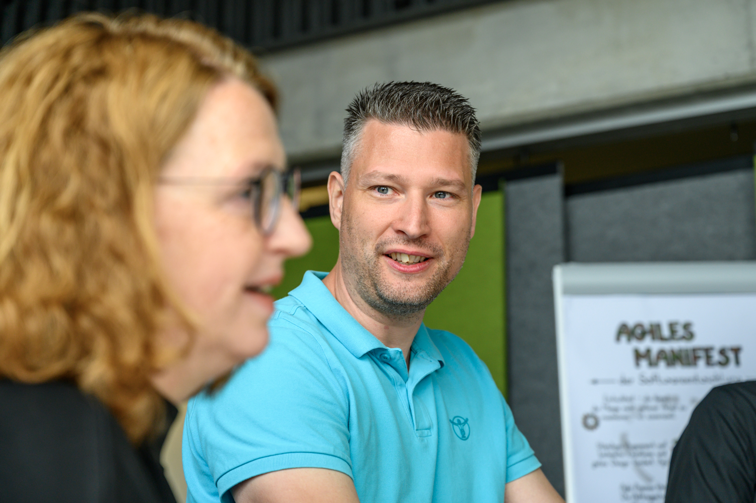 Gitta und Christian, Mitarbeitende der HEC, vor einem Plakat mit dem Agilen Manifest