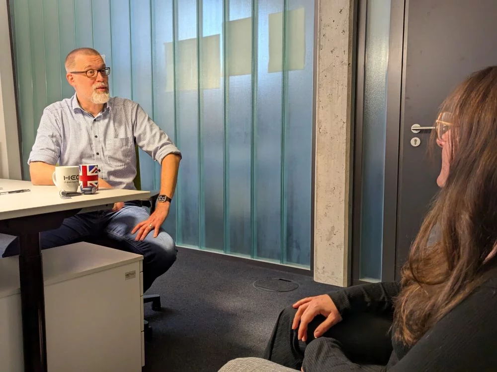 Tim und eine Kollegin sitzen im Büro und diskutieren.