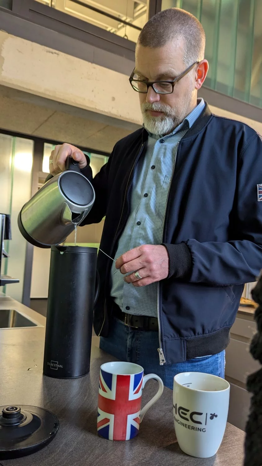 Tim steht in der HEC Küche und gießt sich eine Kanne Tee auf.