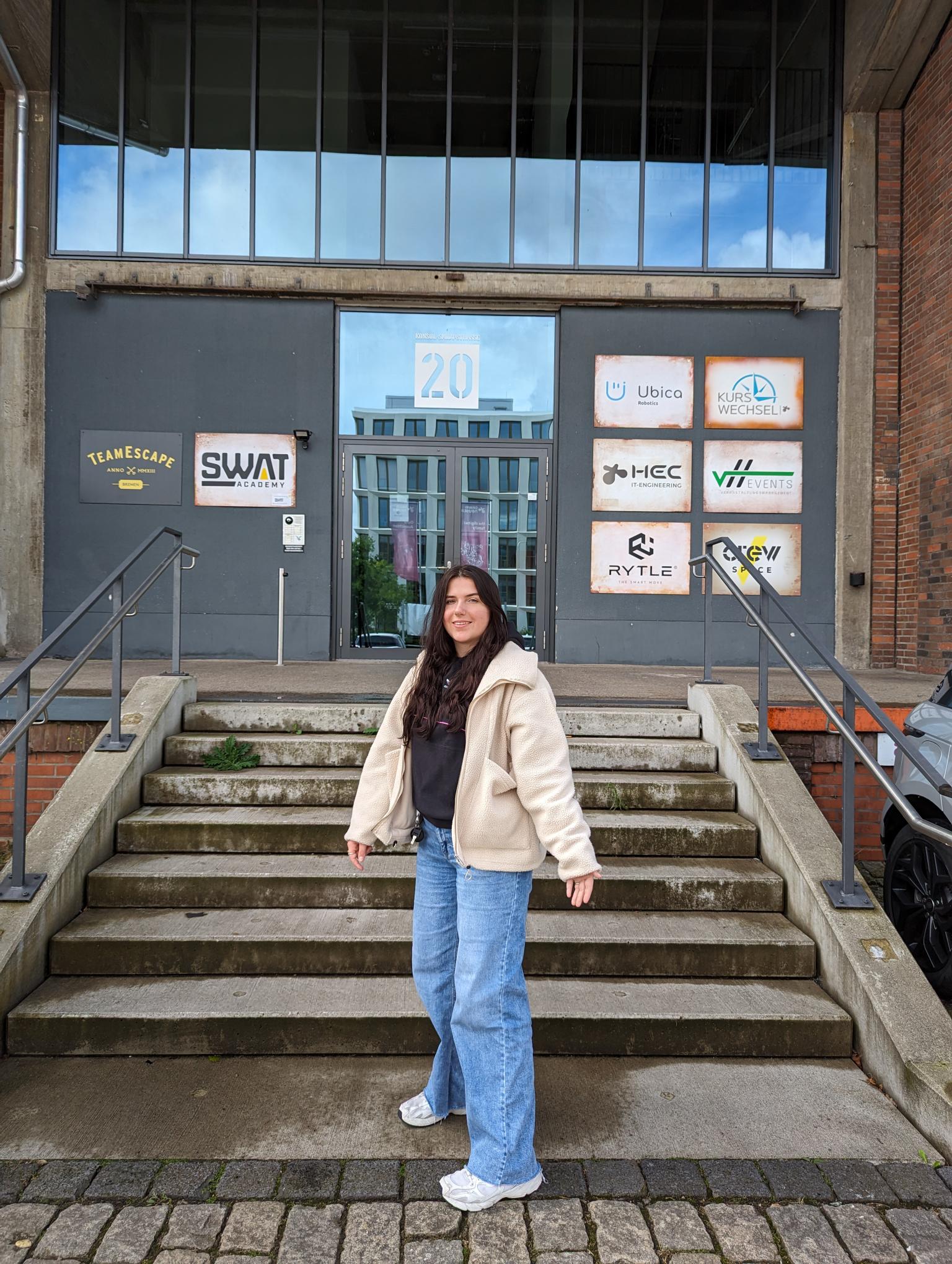 Lara steht vor dem Eingang des Schuppen Eins zur HEC GmbH