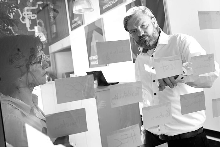 zwei Personen vor einer Glaswand