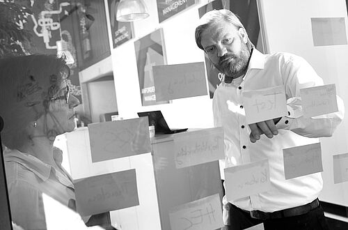 zwei Personen vor einer Glaswand