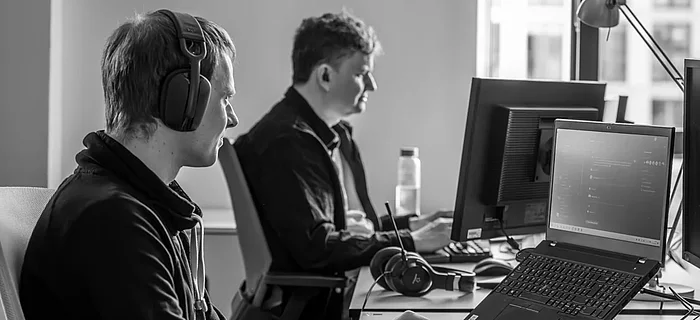 Zwei Softwareentwickler arbeiten fokussiert an ihren PCs