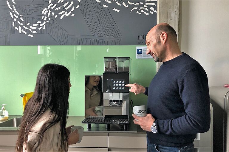 Zwei Personen an einem Kaffeevollautomaten