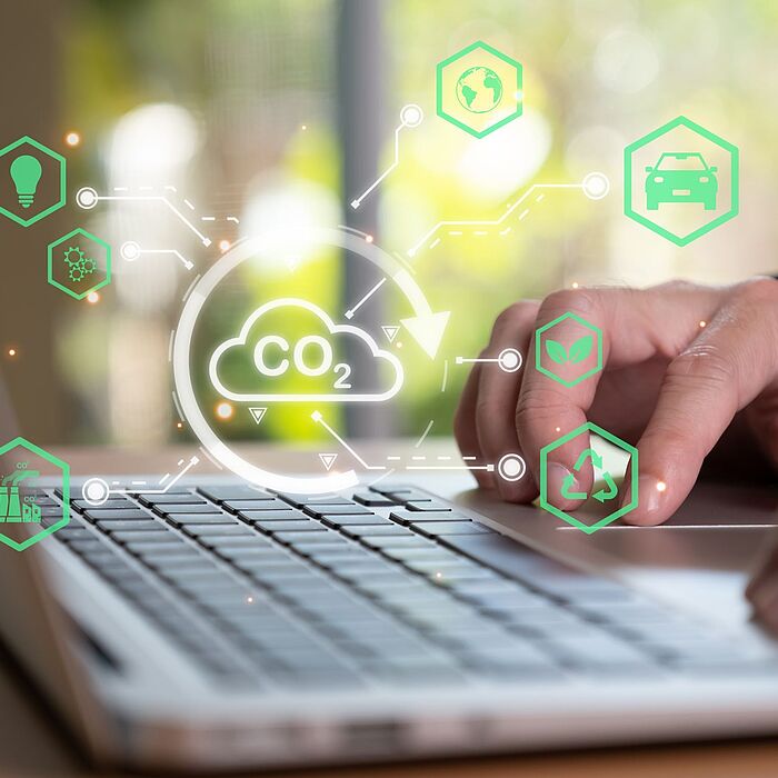 Hände auf Laptoptastatur mit visueller Wolke zum Thema Umweltschutz