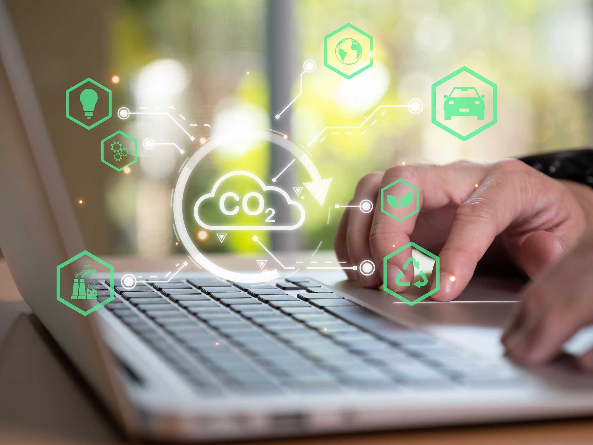 Hände auf Laptoptastatur mit visueller Wolke zum Thema Umweltschutz