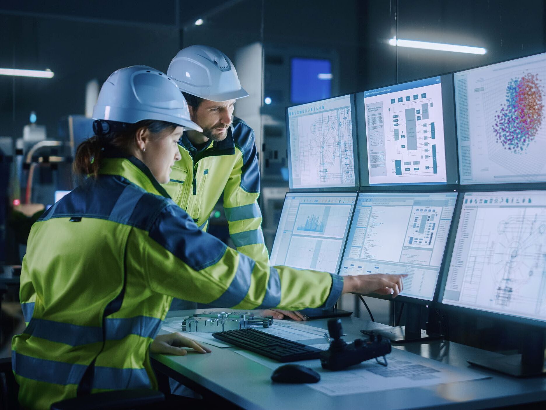 Industrie 4.0 automatisierte Vorhersage Mann und Frau in Sicherheitsbekleidung schauen in einem Kontrollraum auf Monitore