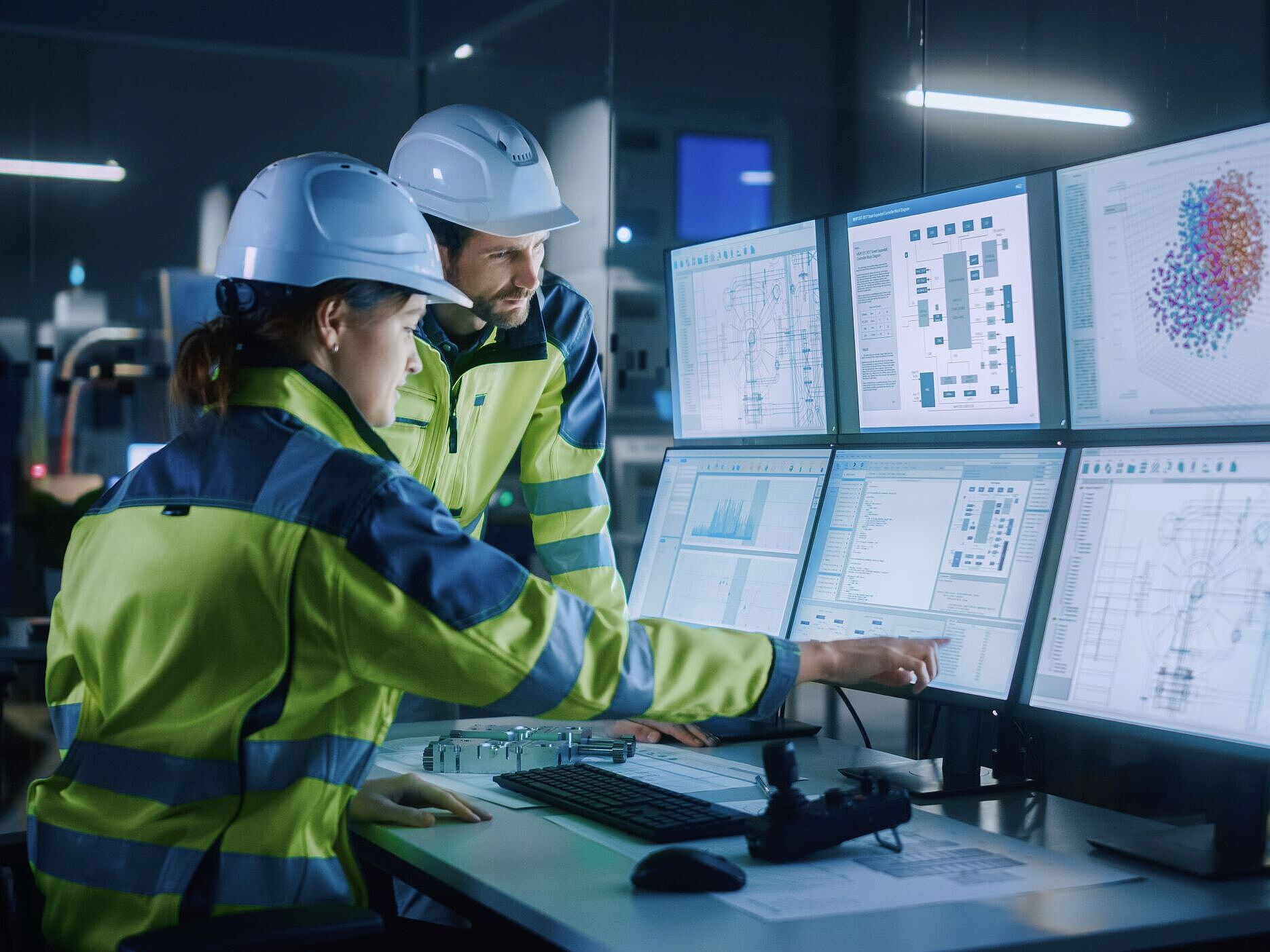 Industrie 4.0 automatisierte Vorhersage Mann und Frau in Sicherheitsbekleidung schauen in einem Kontrollraum auf Monitore