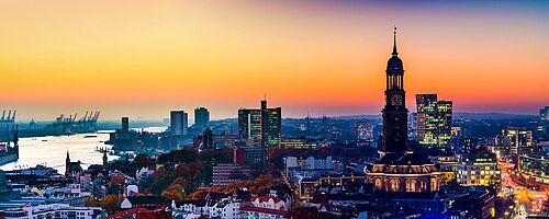 Digitalisierung Hafenlogistik: Blick über den Hamburger Michel zum Hafen bei Sonnenuntergang