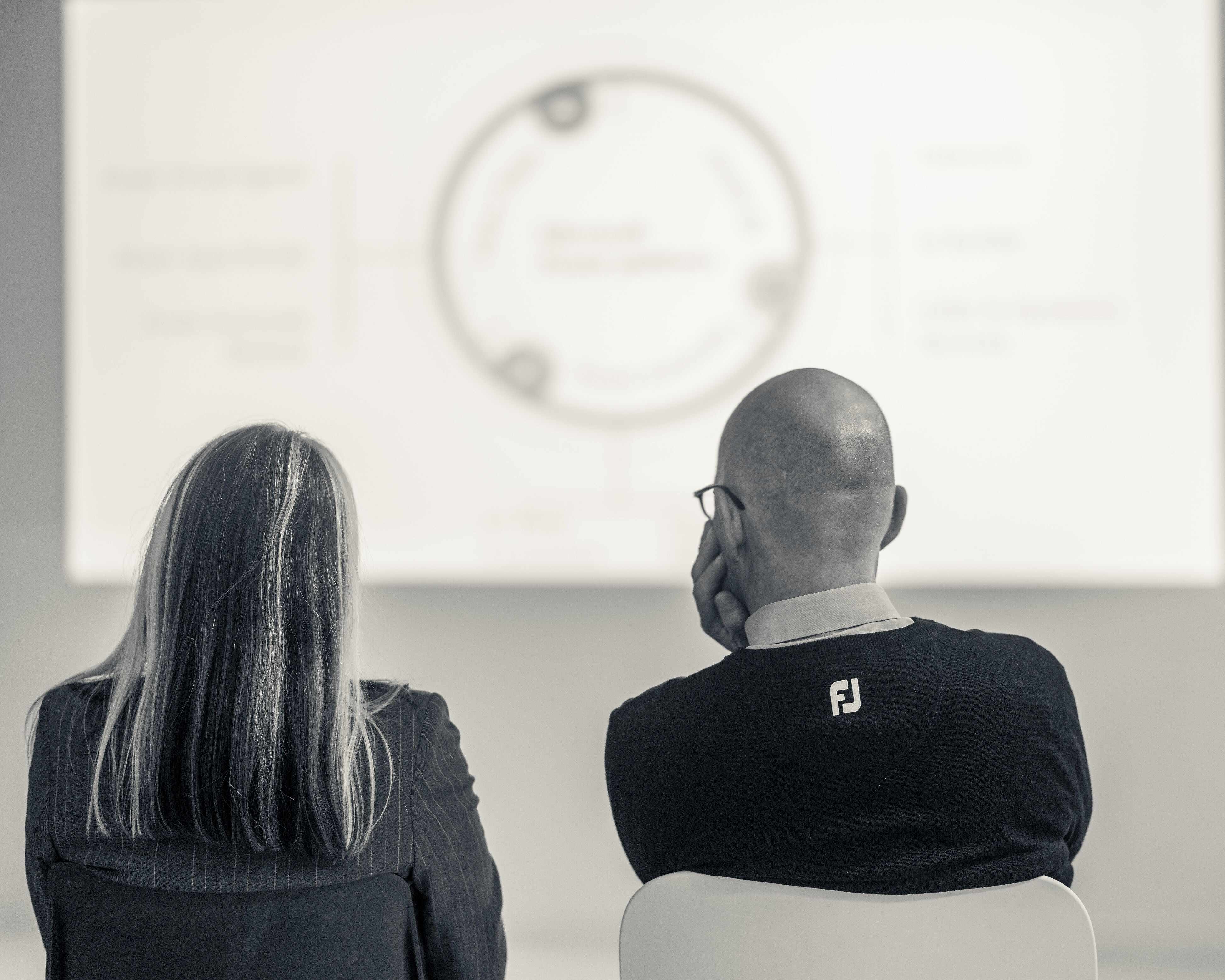 Eine Frau und ein Mann schauen auf eine Präsentation.