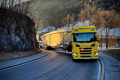 Ein gelber Schwertransport-LKW fährt um eine Kurve