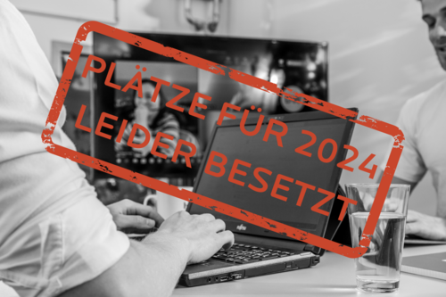 Schwarz-Weiß-Foto eines Laptops. Auf dem Bild ist ein roter Stempel mit den Worten: Plätze für 2024 leider besetzt!