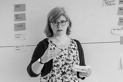 Eine Frau erläuternd vor einem Whiteboard