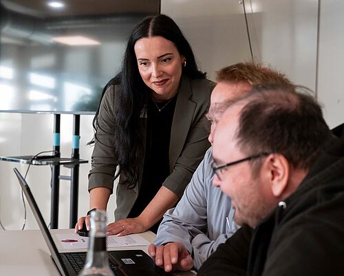 Charlene Walther erklärt Workshop-Teilnehmenden am Laptop, wie sich digitale Barrierefreiheit umsetzen lässt.