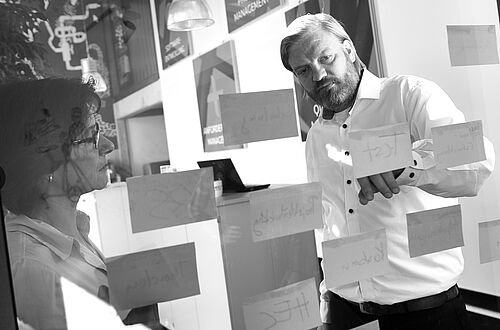 zwei Personen vor einer Glaswand