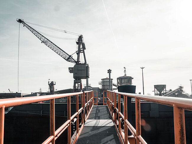 Von einer Brücke aus blickt man auf einen Kran und Fördertürme im Hafen von Oldenburg.