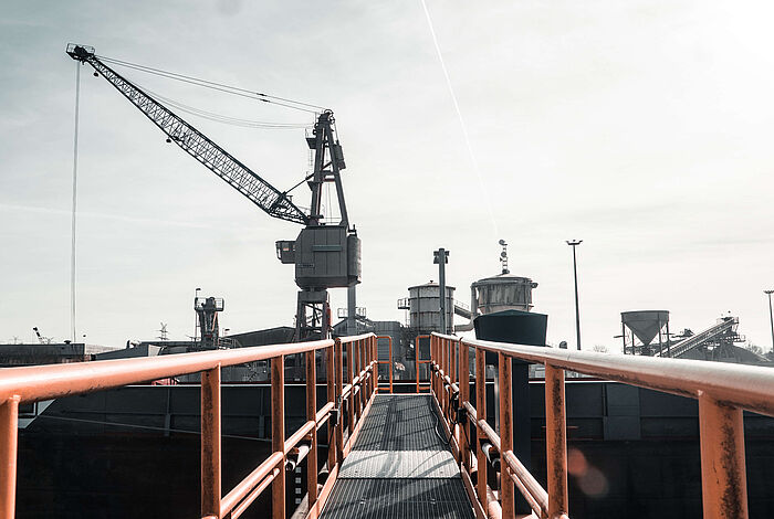 Von einer Brücke aus blickt man auf einen Kran und Fördertürme im Hafen von Oldenburg.
