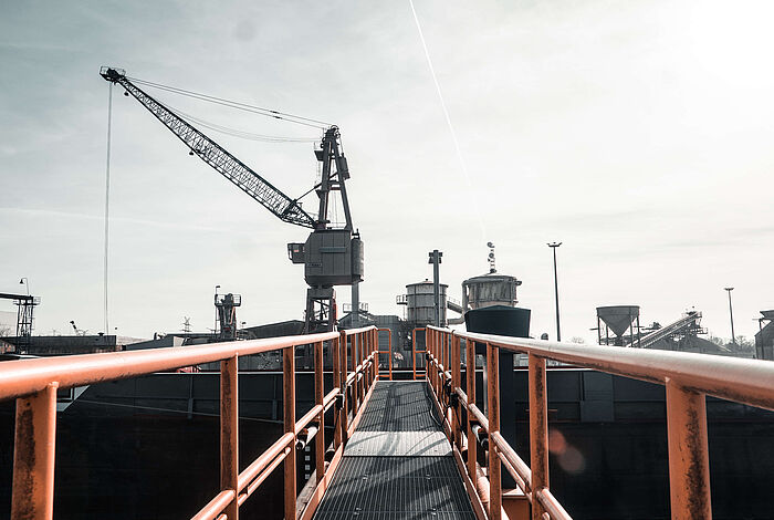 Von einer Brücke aus blickt man auf einen Kran und Fördertürme im Hafen von Oldenburg.