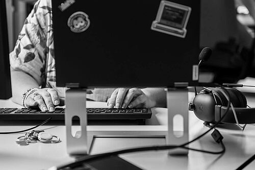 augeklapptes Laptop, dahinter die Hände einer Frau an der Tastatur herangezoomt