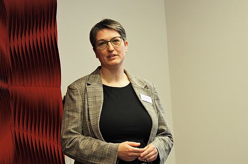 Eine Frau steht vor einer Wand.