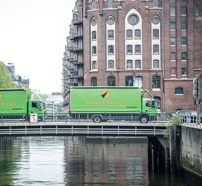 Bild von zwei LKW's, welche eine Brücke überqueren. 