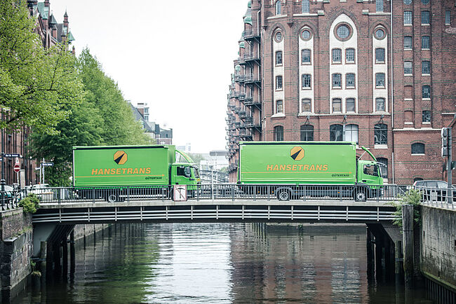Bild von zwei LKW's, welche eine Brücke überqueren. 