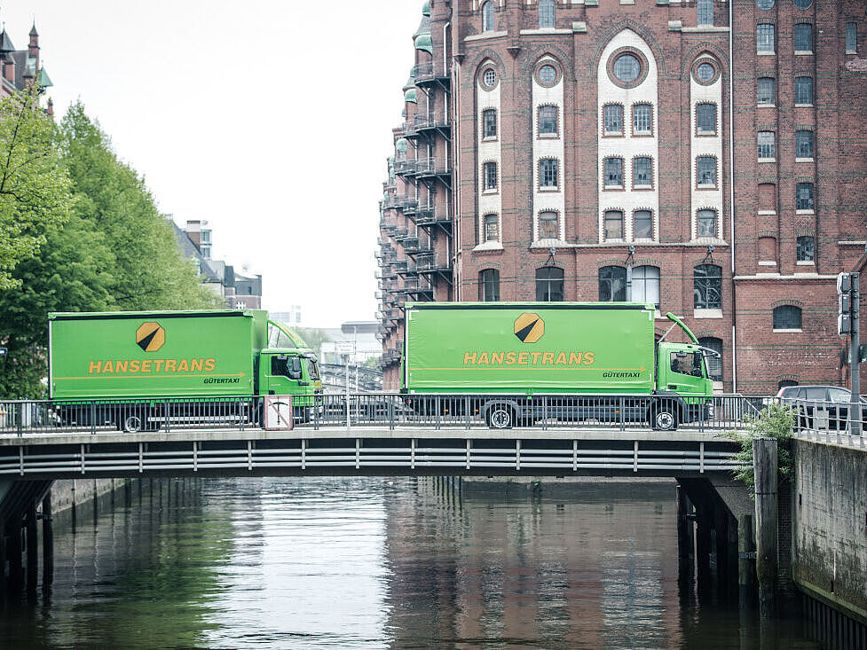 Bild von zwei LKW's, welche eine Brücke überqueren. 