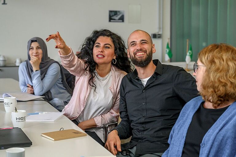 Drei Frauen und ein Mann diskutieren in einem Meeting.