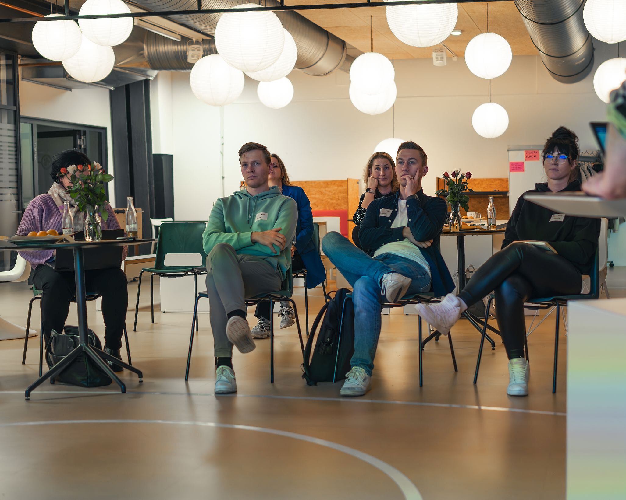 Menschen sitzen auf Stühlen und hören einem Vortrag zu.