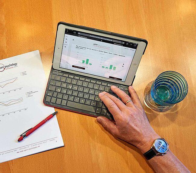 Blick auf einen Schreibtisch mit Laptop und Analysen