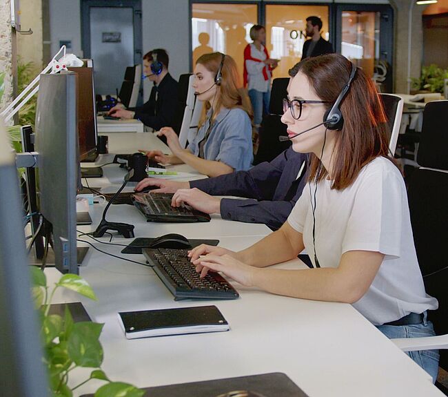 Personen in einem Großraumbüro mit Headsets