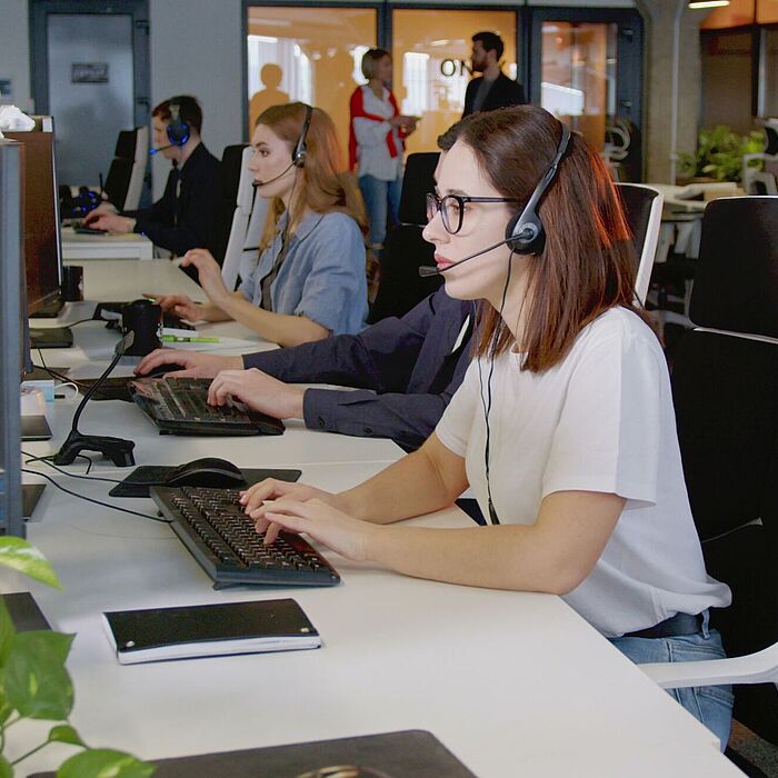 Personen in einem Großraumbüro mit Headsets