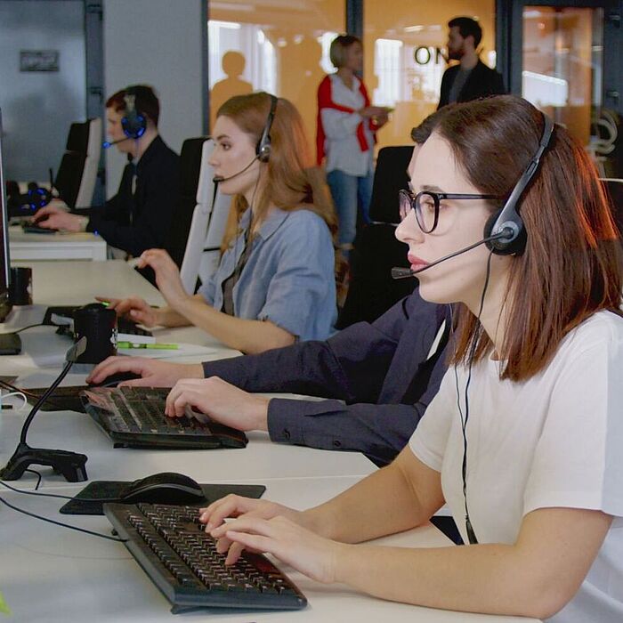 Personen in einem Großraumbüro mit Headsets
