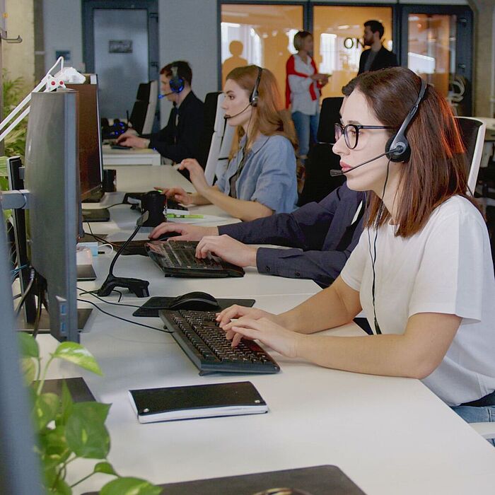 Personen in einem Großraumbüro mit Headsets