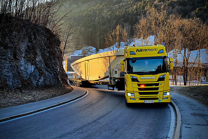 Ein gelber Schwertransport-LKW fährt um eine Kurve