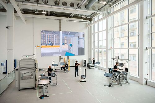 In einer hochdigitalisierten Produktionshalle arbeiten Forscher an verschiedenen Stationen.