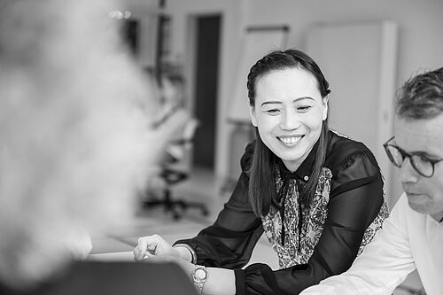 Eine Frau an einem Tisch im Workshopraum lächelt.