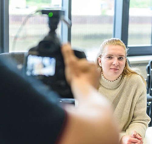 Eine Frau, die in eine Kamera blickt.