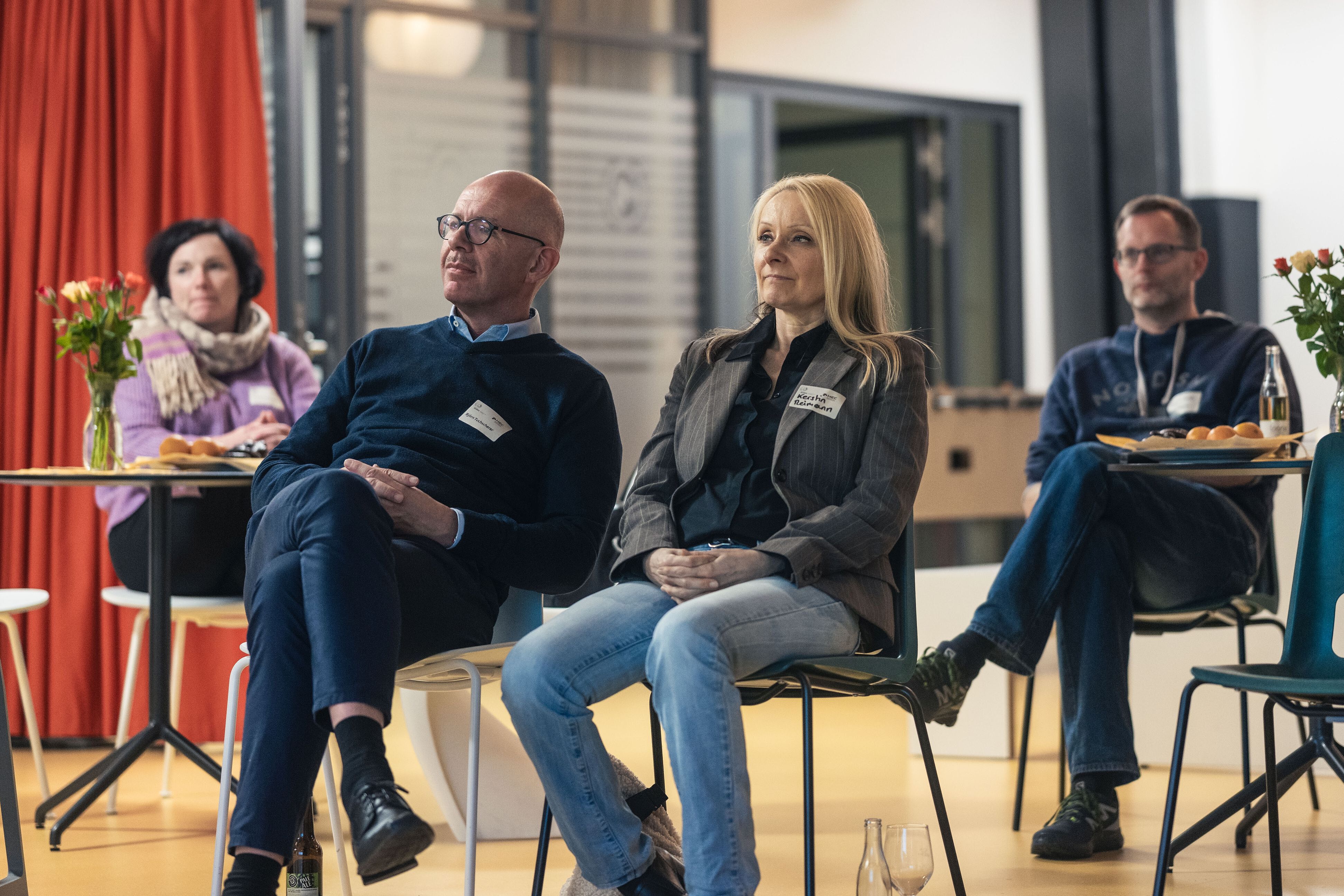 Personen sitzen auf Stühlen und hören einem Vortrag zu.