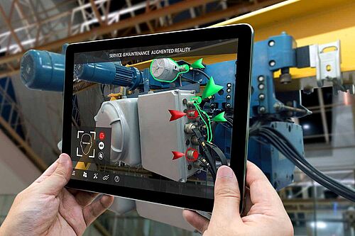 Hände halten ein Tablet vor eine Maschine