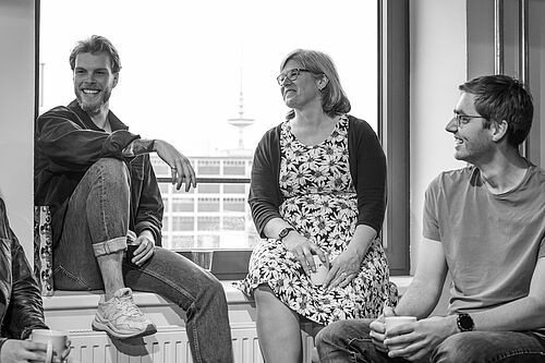 Vier Menschen machen Pause und stehen und sitzen im Fensterrahmen