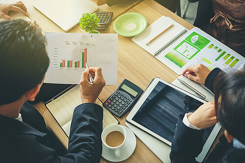 Zwei Personen an einem Tisch lesen Ausdrucke mit Diagrammen