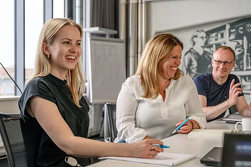 Menschen sitzen an einem Besprechungstisch und lachen über etwas