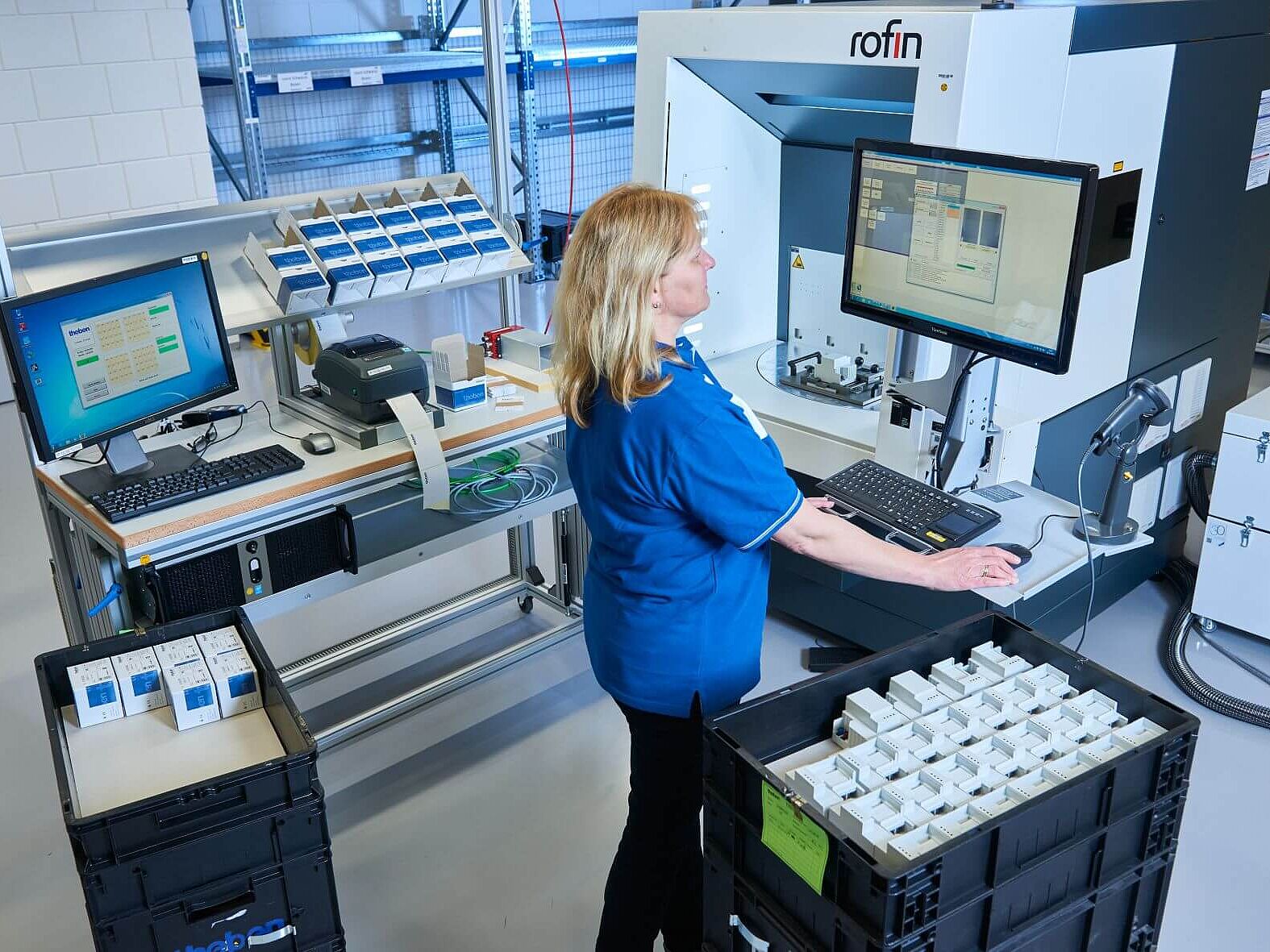 Theben-Smart-Energy_Produktion Eine Frau bedient über eine Tastatur und Bildschirm eine Produktionsanlage
