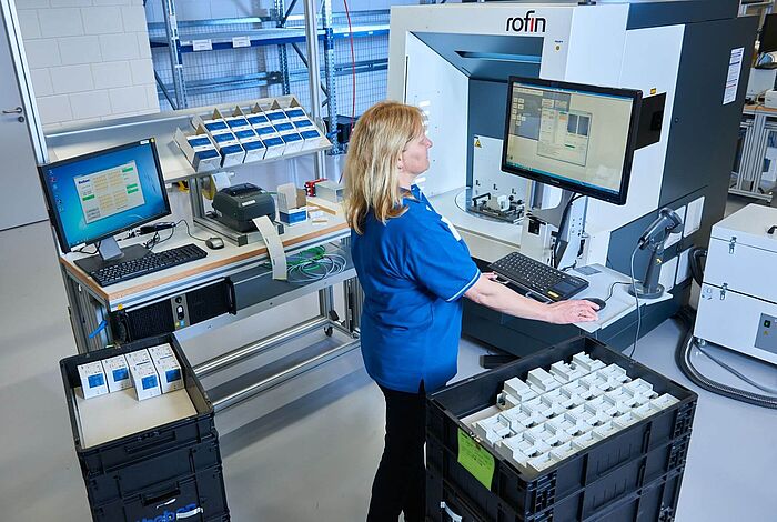 Eine Frau bedient über eine Tastatur und Bildschirm eine Produktionsanlage