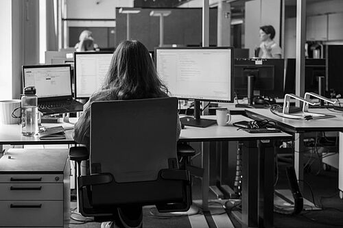 Eine Frau arbeitet an einem Laptop am Schreibtisch im Büro