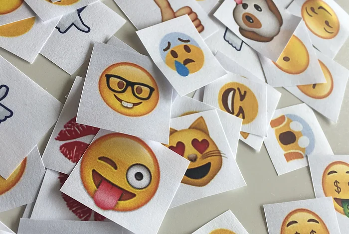 Ausgedruckte Emojis liegen auf einem Tisch.