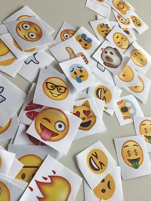 Ausgedruckte Emojis liegen auf einem Tisch.