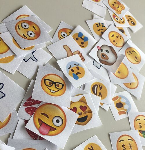 Ausgedruckte Emojis liegen auf einem Tisch.
