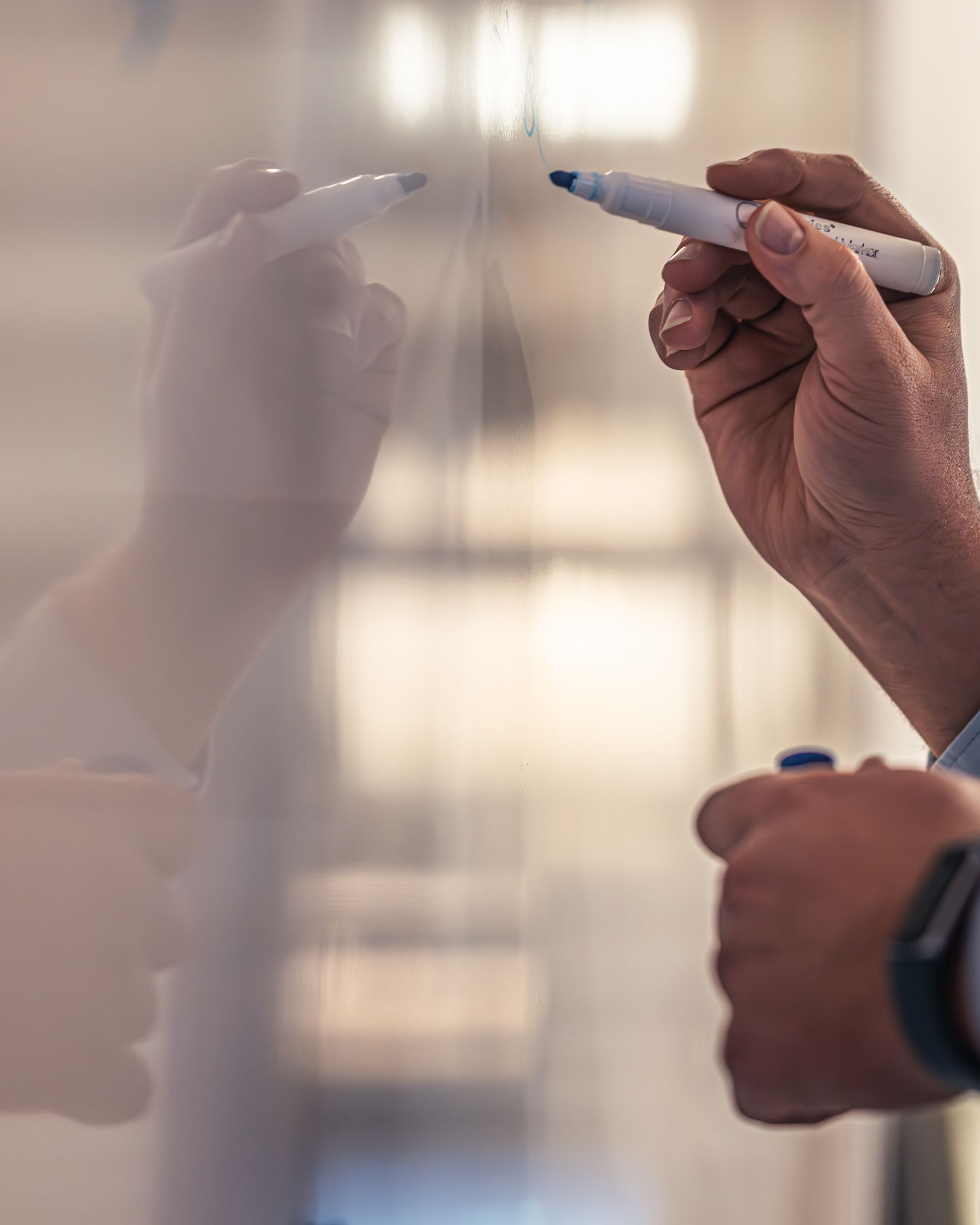 Hände schreiben mit einem Stift an eine Wand.